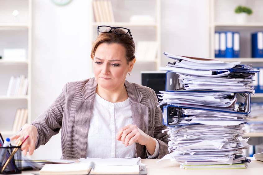 Woman at a desk with a pile of binders