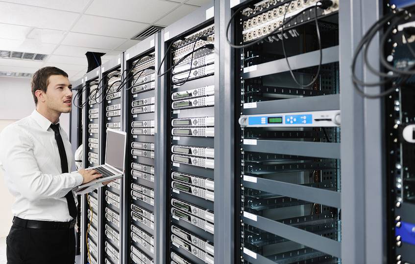 Man in a server room with a laptop