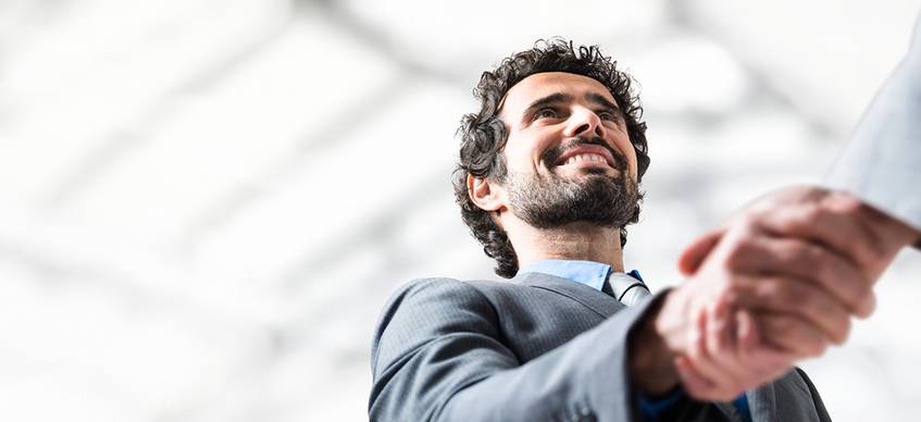 Man in a business suit shaking someones hand.